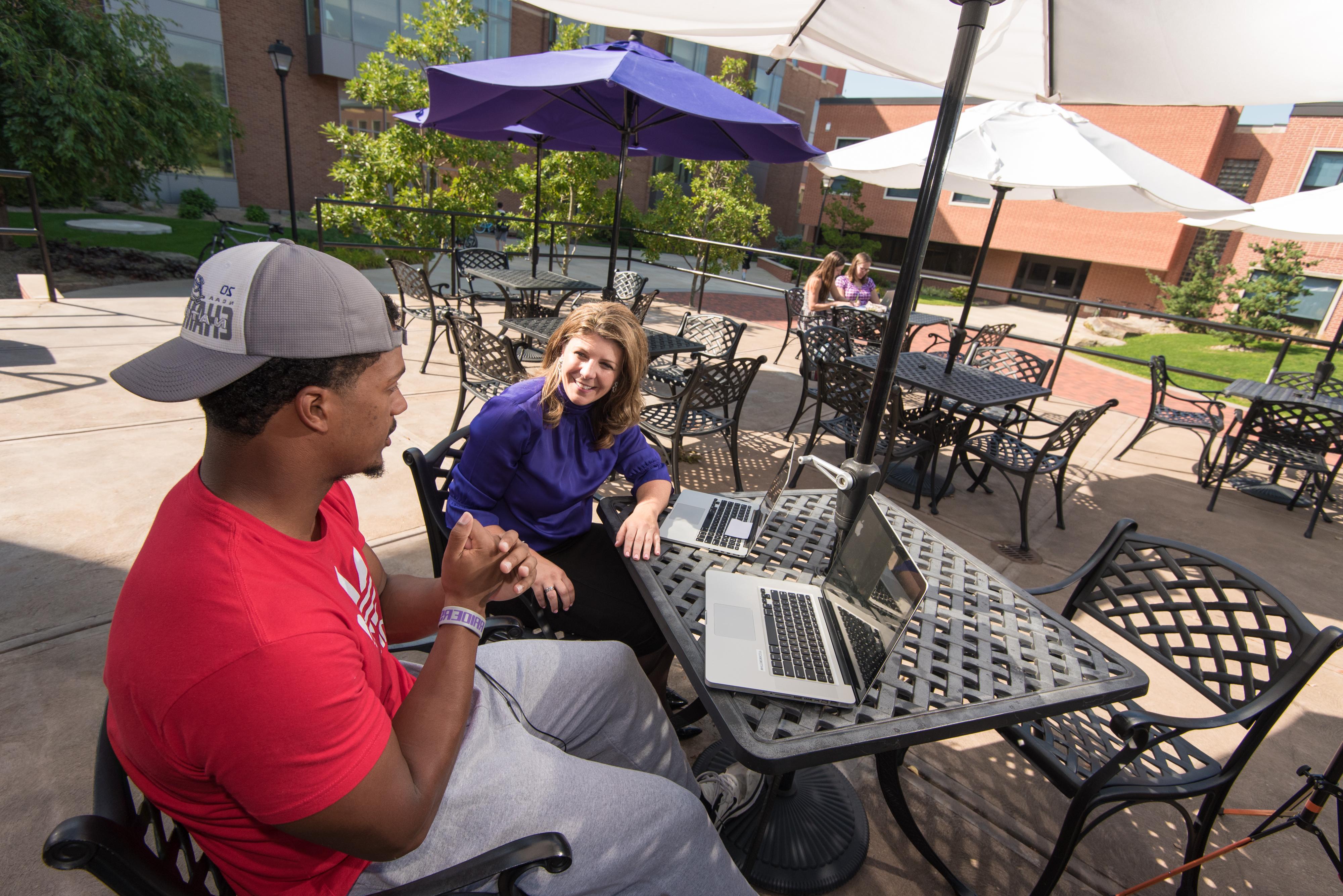 Student 和 professor using laptop on patio of 图书馆