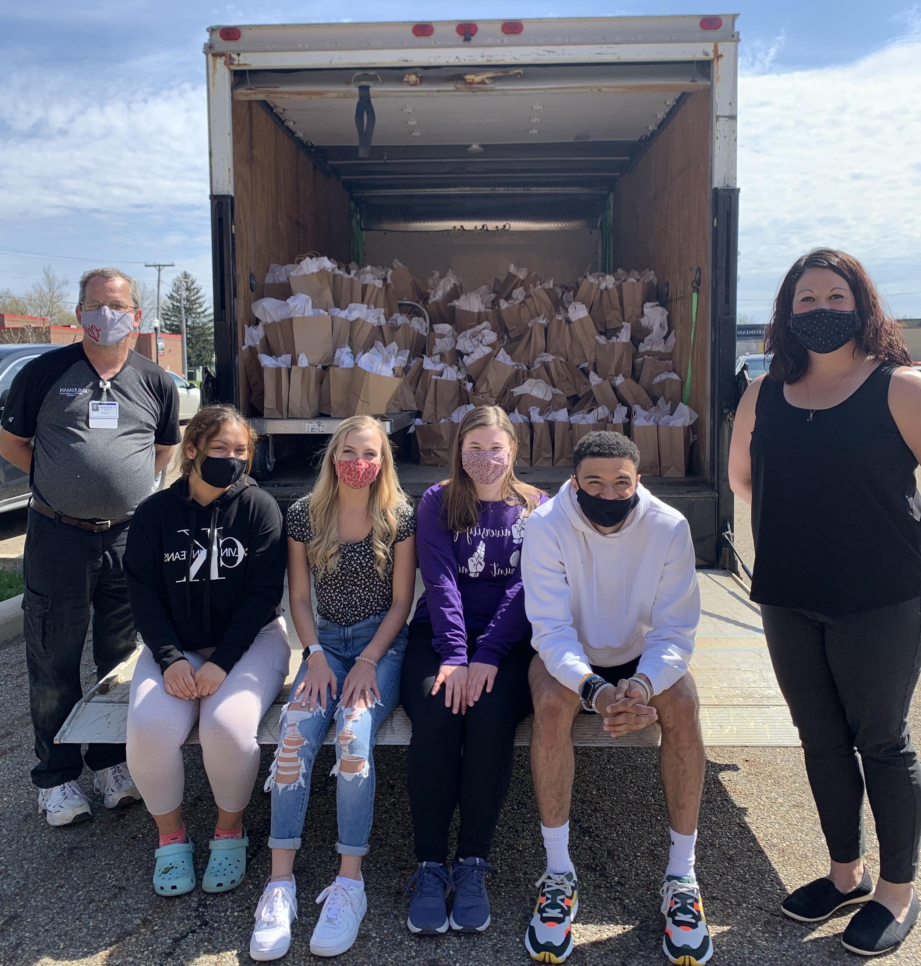 students in front of semi truck filled with bags